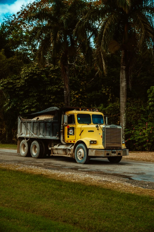 a yellow dump truck driving down a road