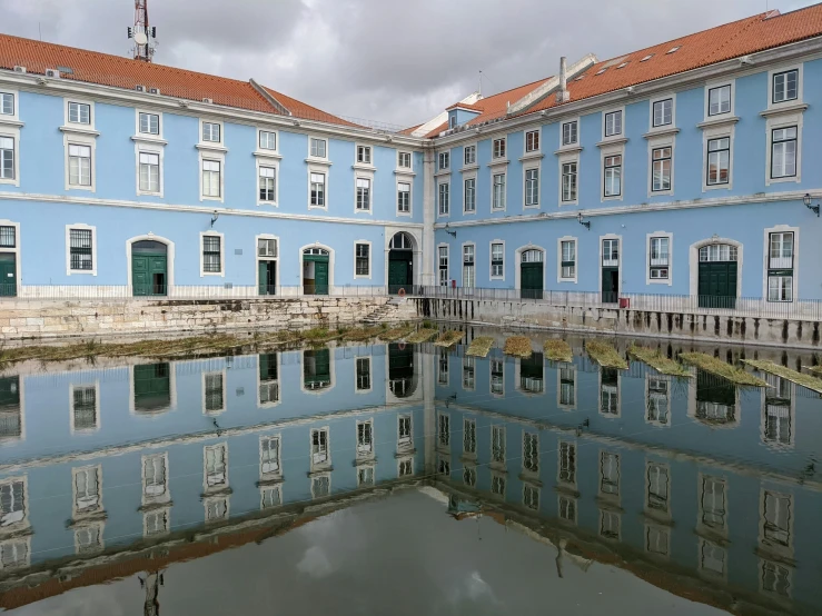 a blue building with orange tiles reflected in water