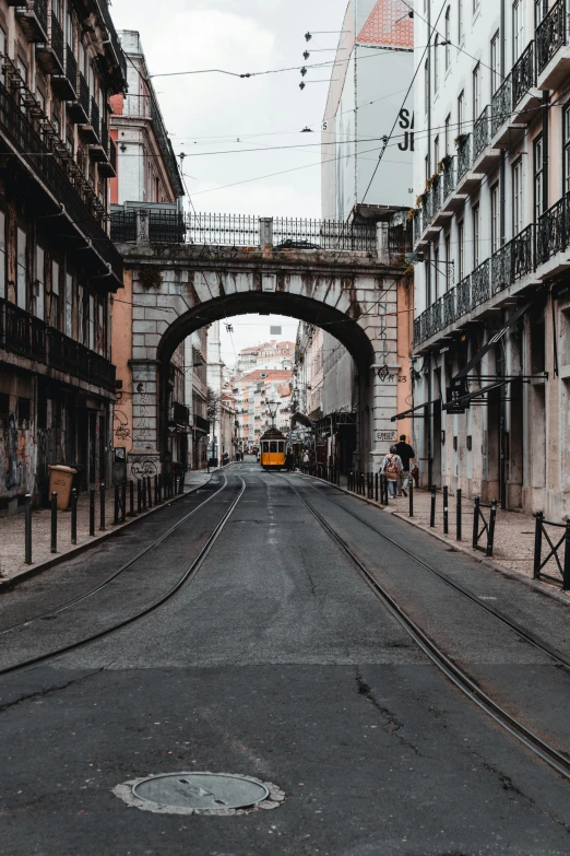 people walking on a city street while a bus goes under an overpass