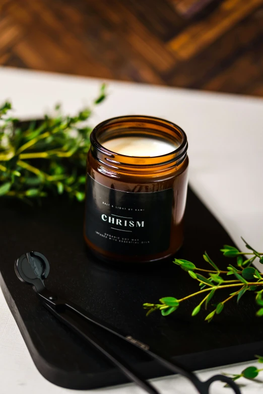 a glass jar of lotion next to a couple of green plants