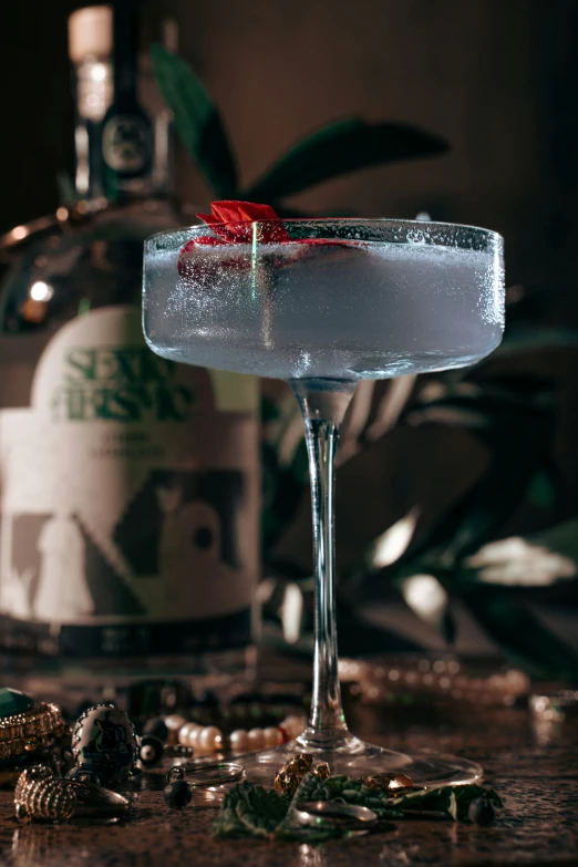 a glass filled with an alcoholic drink next to jewelry