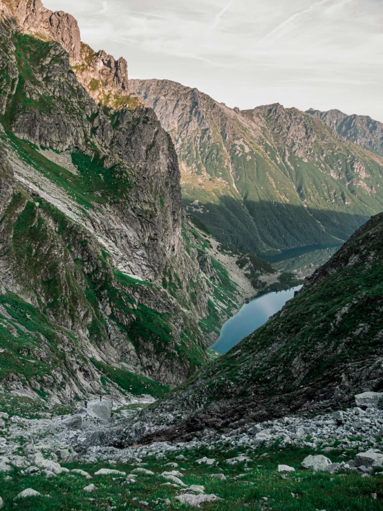 a couple of mountain sides and water surrounded by grass