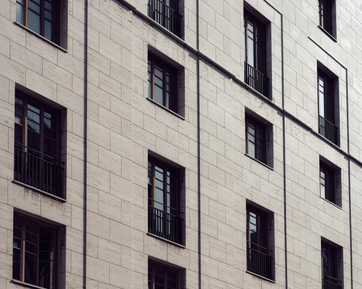 two clocks on a building with several windows