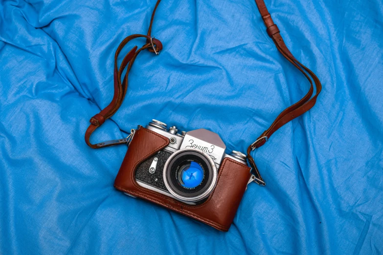 a camera with a brown leather case and a blue cover