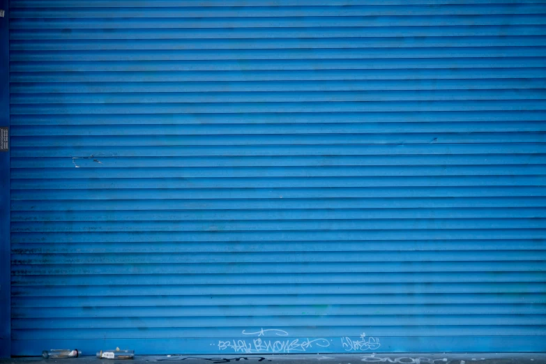 a tall blue wall next to a metal structure