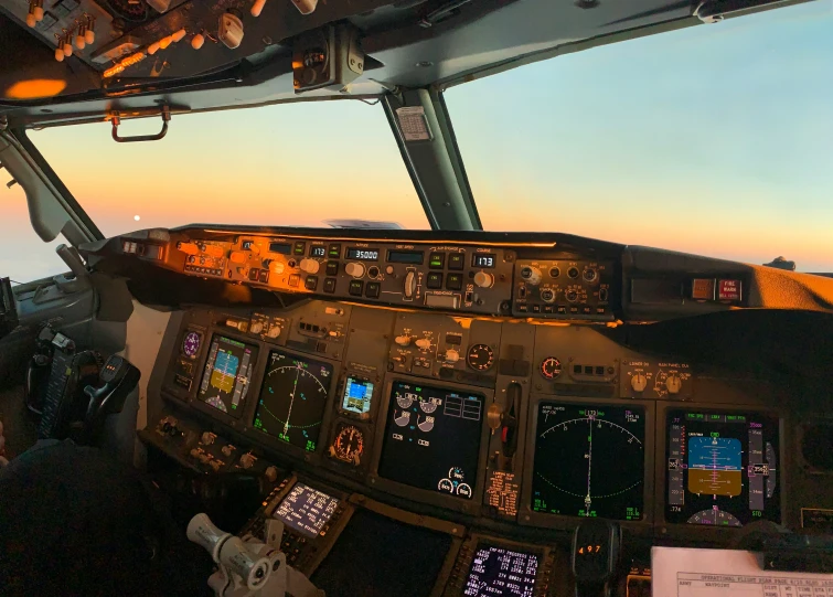an airplane's cockpit with illuminated controls at sunset