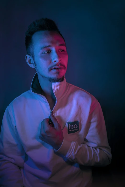 a man standing in the dark wearing a white jacket