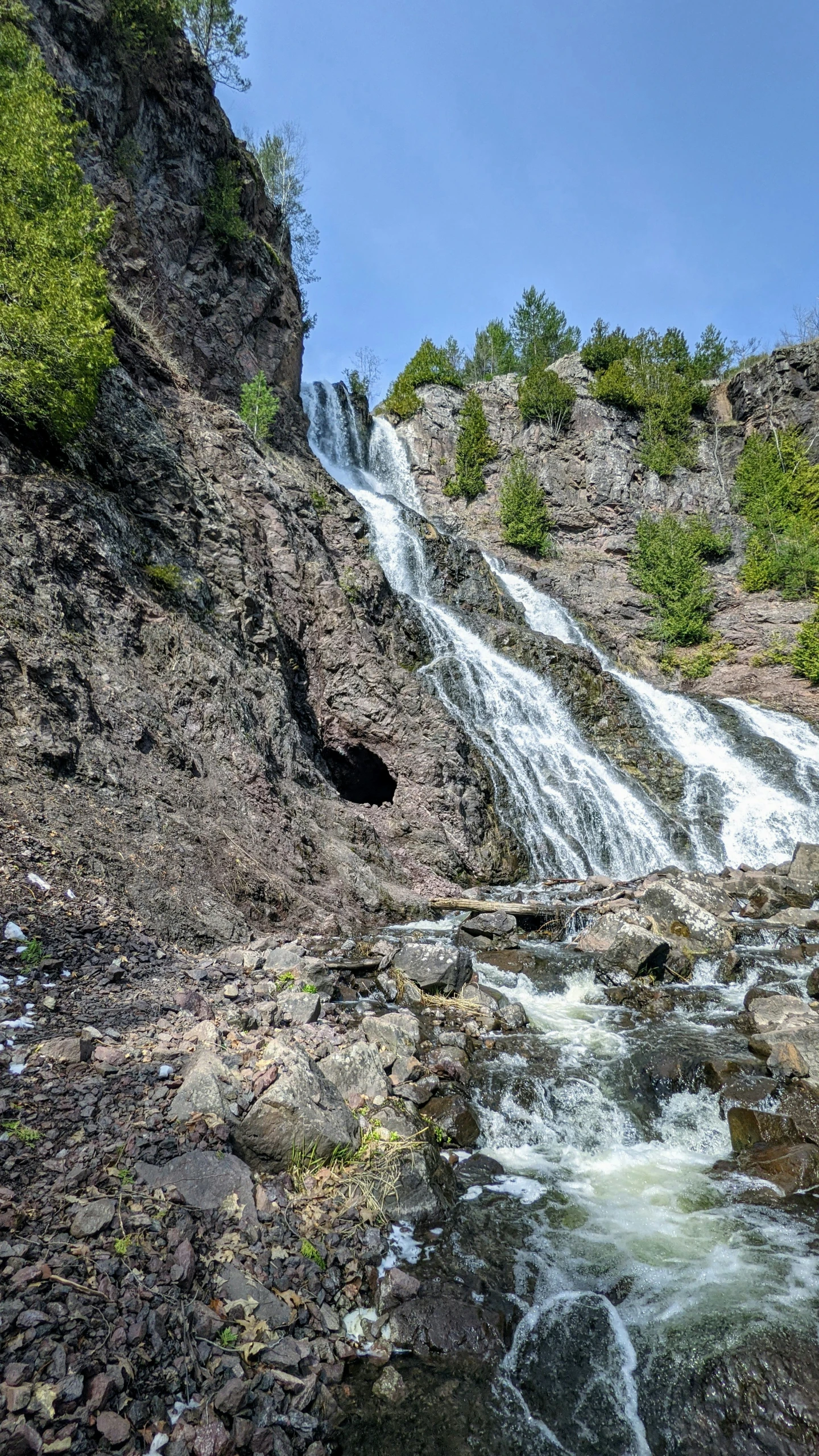 a waterfall cascading from the cliff down to a small river