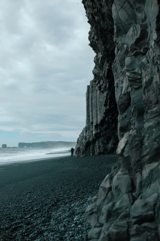 a black and gray po of the beach next to rocks