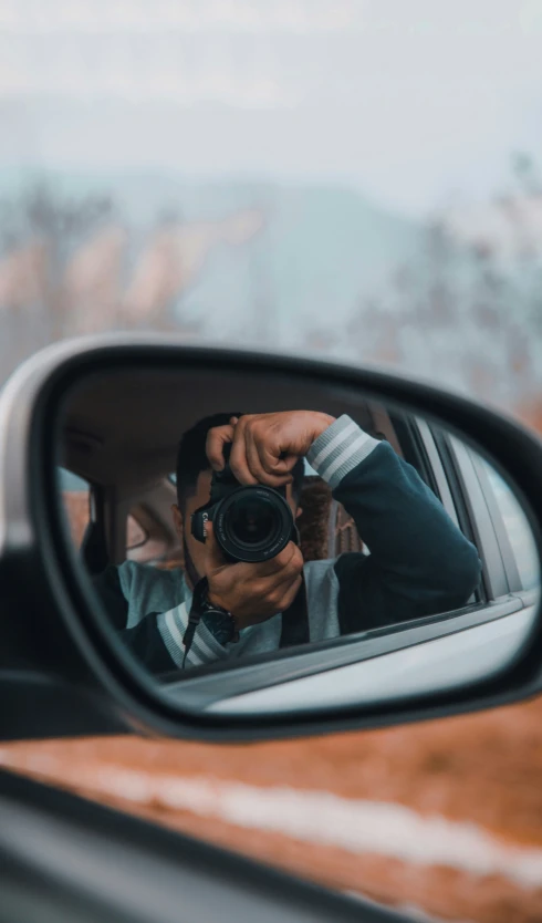 a man with a hat taking a selfie in his car mirror