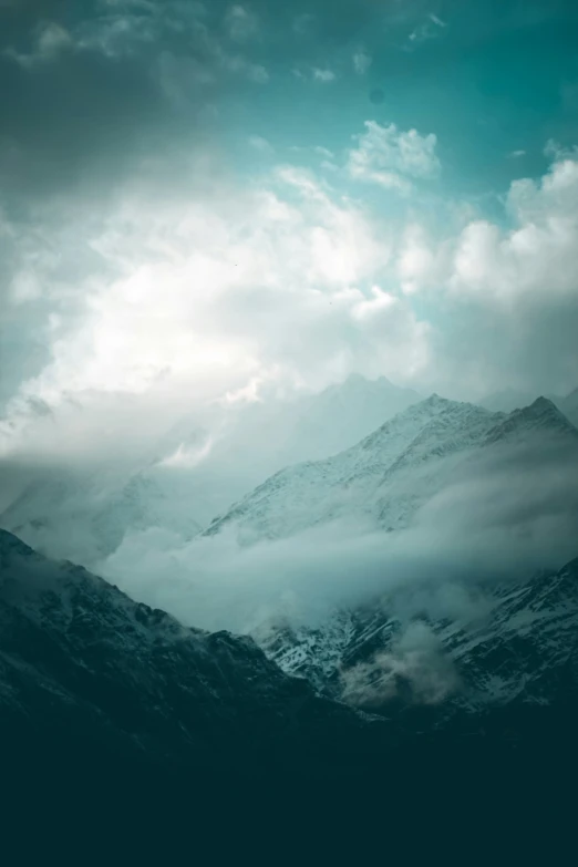 a plane flying over some mountains under a cloudy sky