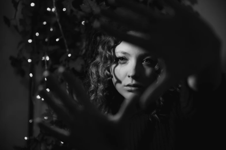 black and white pograph of woman hiding behind flowers