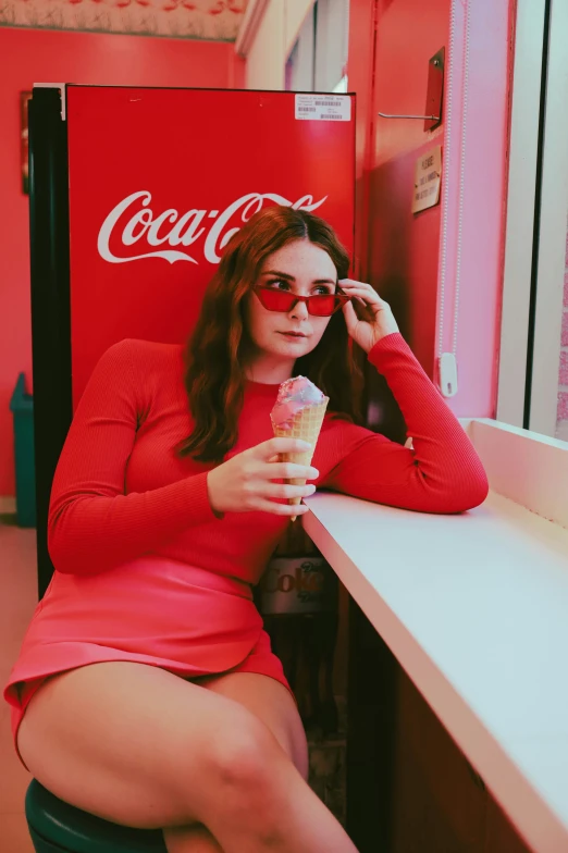 a woman in a dress sitting on a chair holding onto a cup