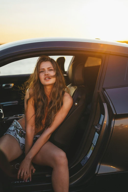 a woman in a short sitting on a car