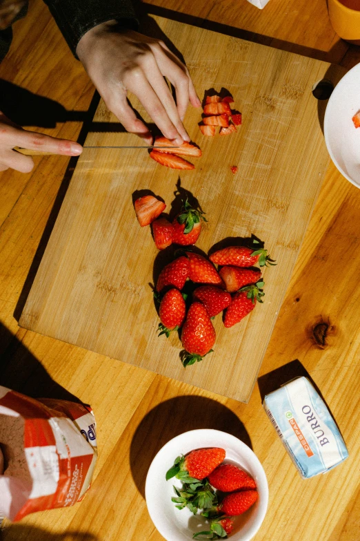 two hands reaching for strawberries on a  board