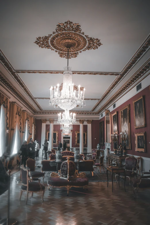 a room with a chandelier, some chairs, table, and two couches