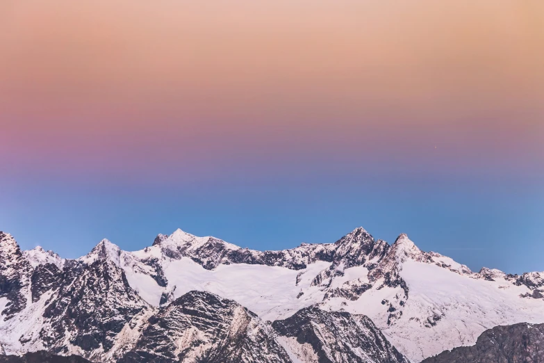 a snow capped mountain range with some clouds above