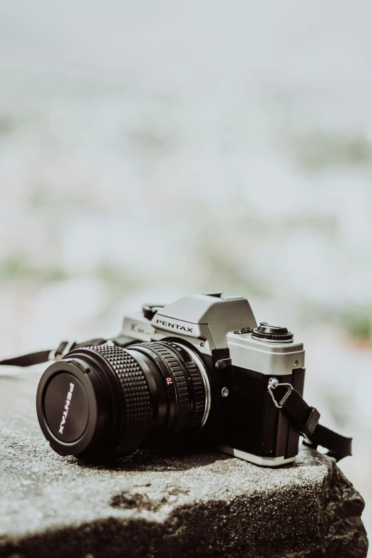 a camera sitting on top of a rock in front of a city