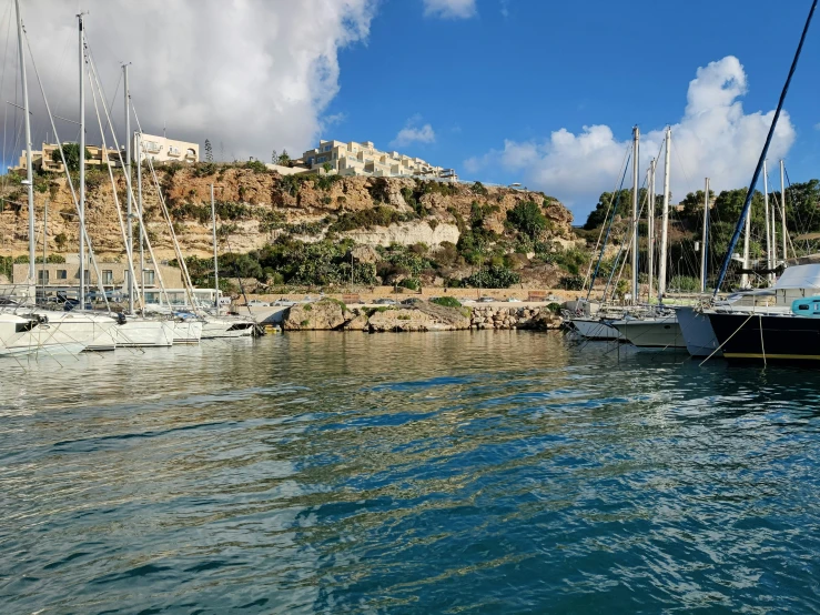 a marina with several boats and large hill in the background