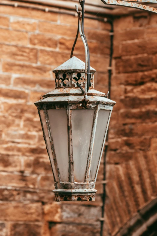 an old - fashioned light hanging from a brown brick wall