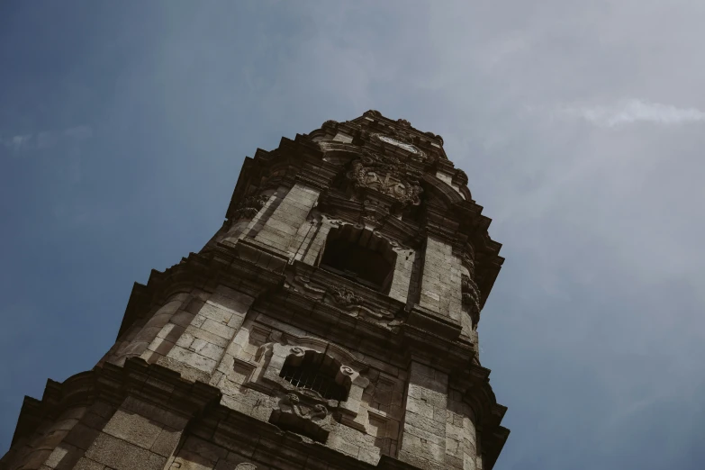 a clock tower with roman numerals against a cloudy blue sky