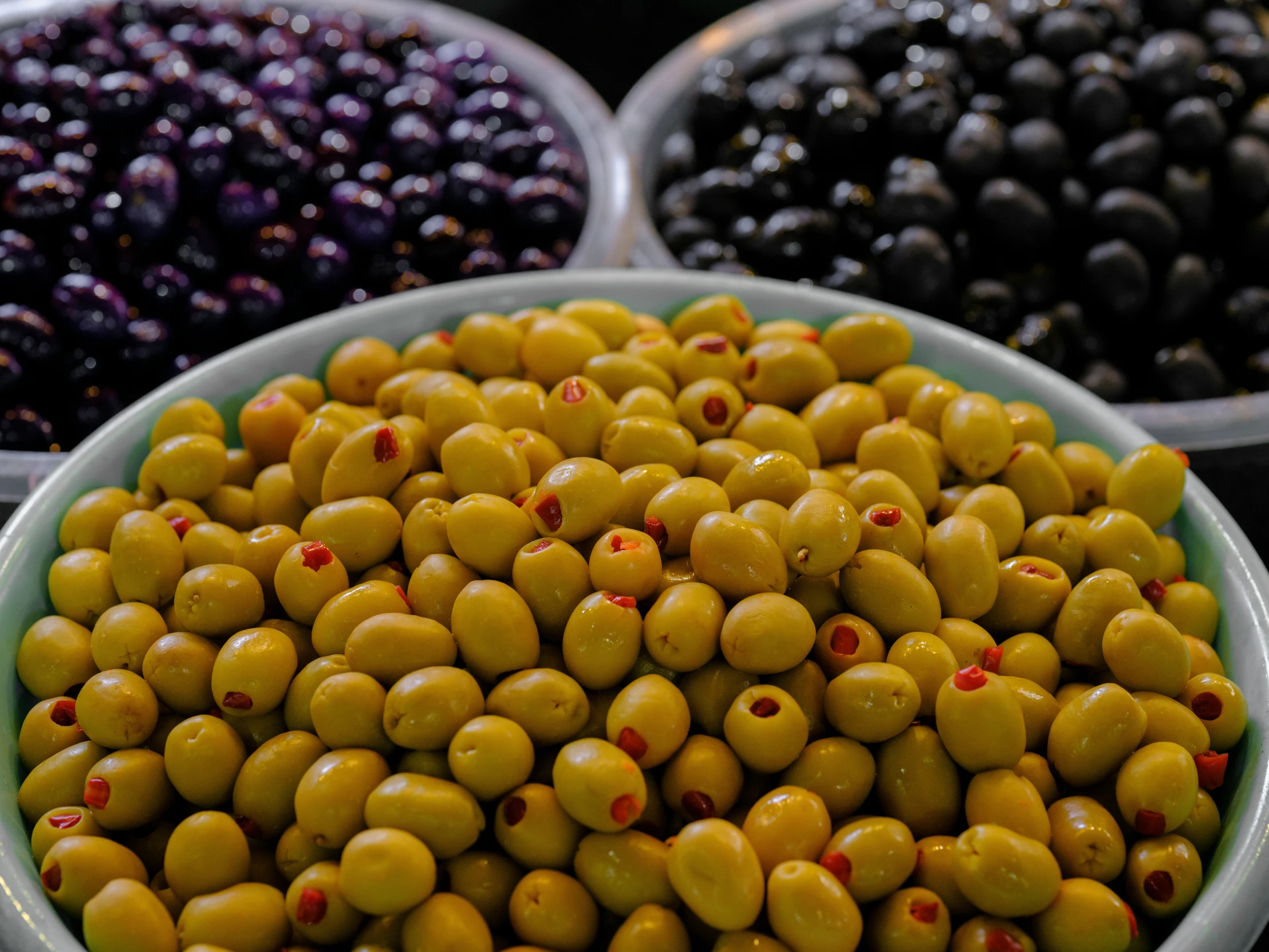 several bowls filled with yellow and purple olives