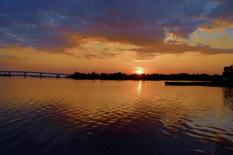 the sun sets over a bridge spanning a river