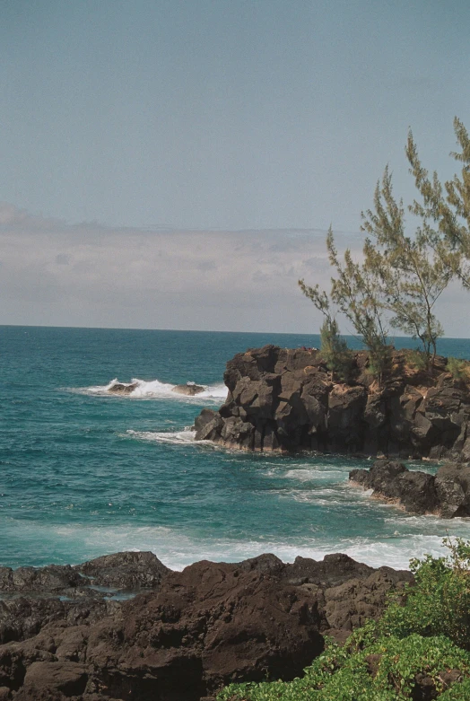 rocks along side the ocean with the waves breaking