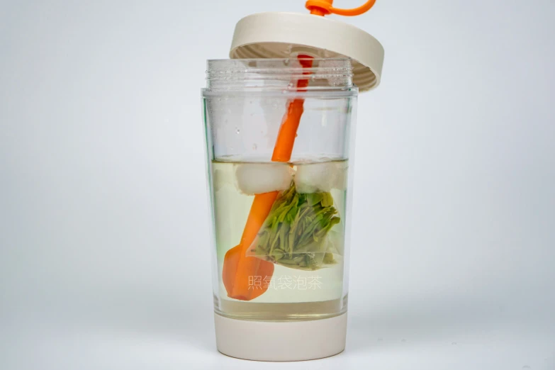 a cup with ice water, carrots and broccoli inside