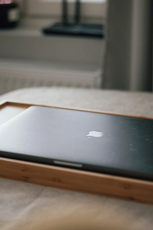 an apple laptop is sitting on a wooden tray