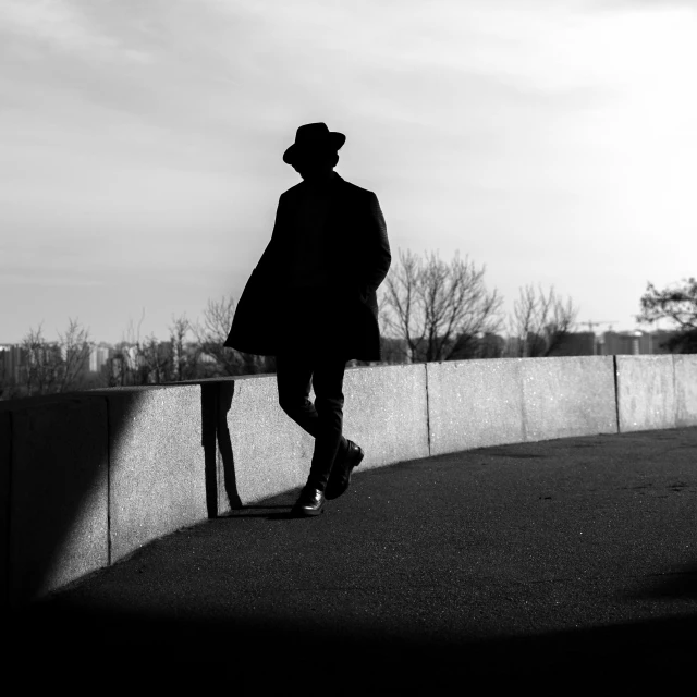 a man walking up to a fence on his coat