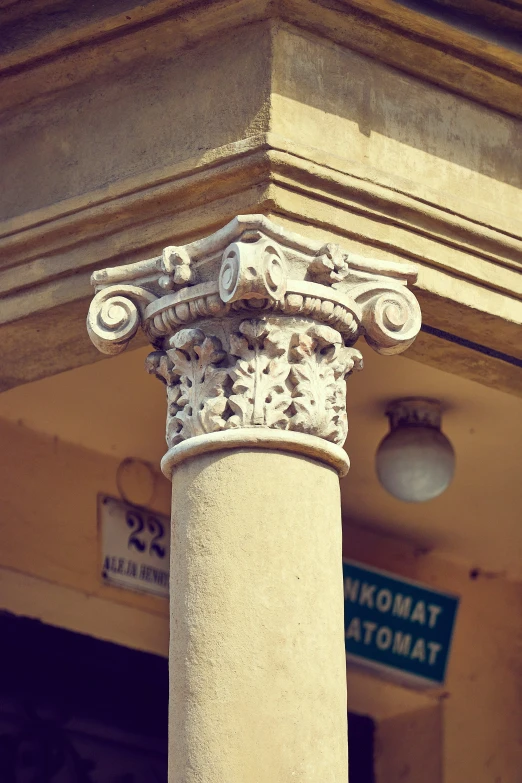 an ornate column on a sidewalk near a sign