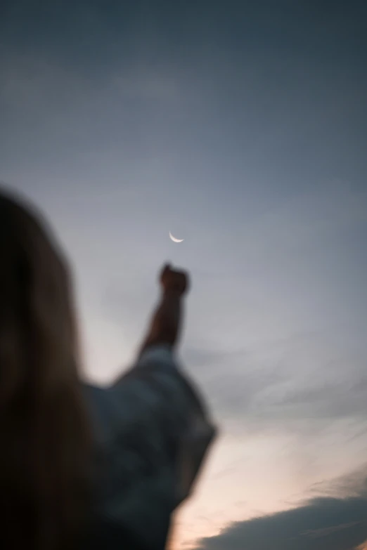 person flying a kite with the moon in the sky