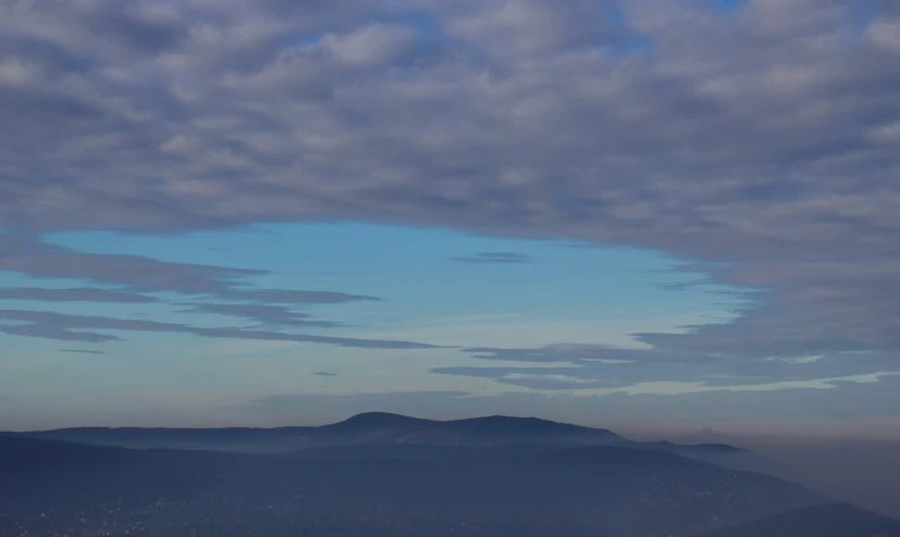 a small plane flying over mountains at dusk