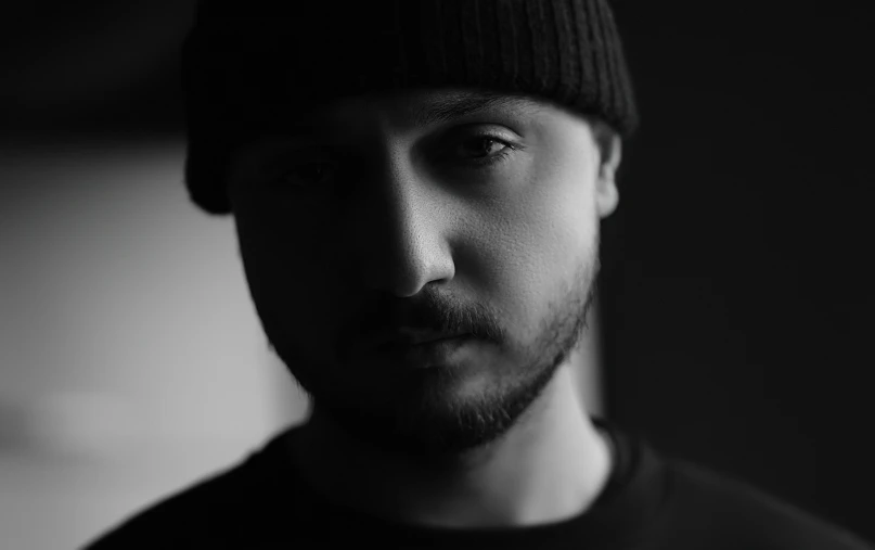 man with black hat standing against wall and looking straight ahead