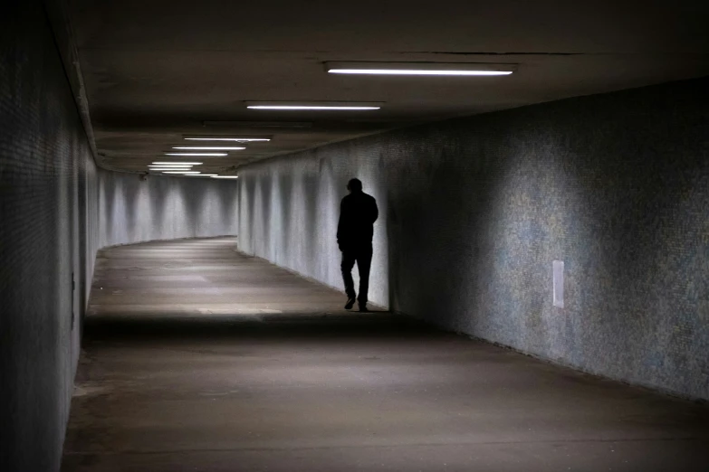 a man stands alone in a dark hallway