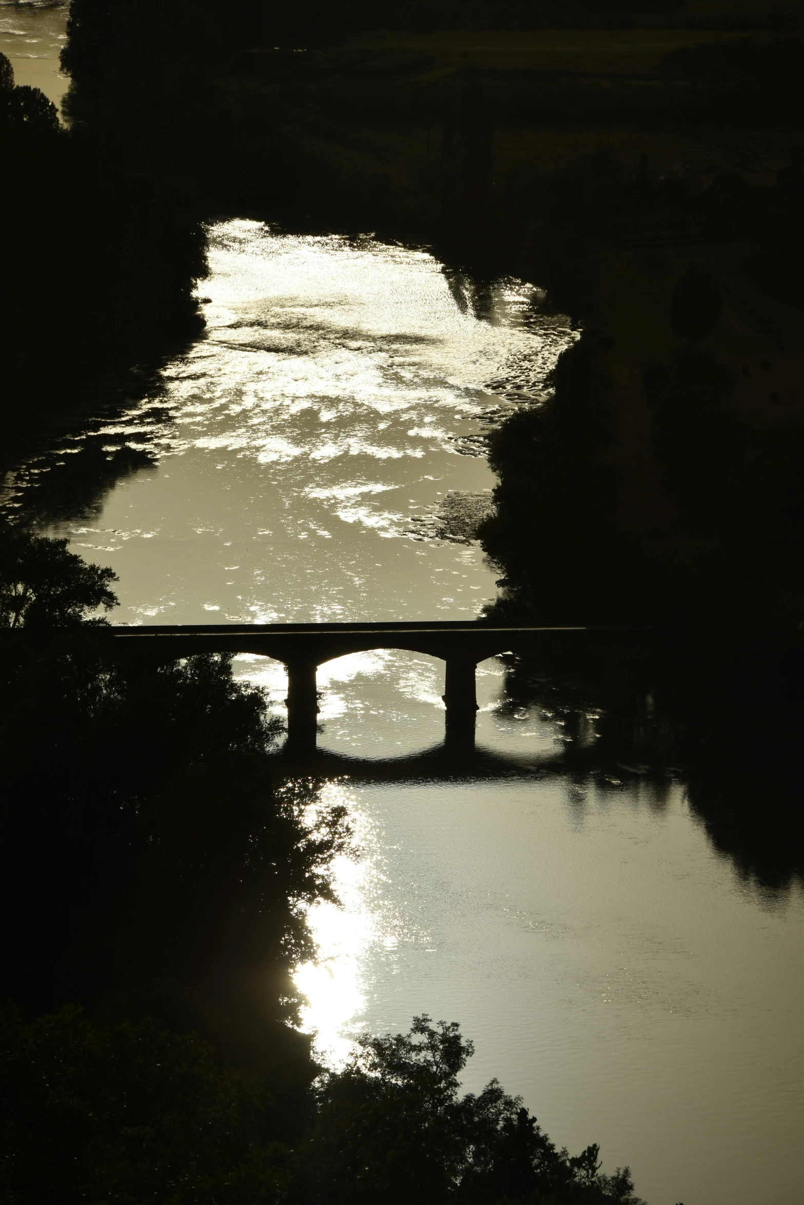 a bridge crosses a river with sunset in the background