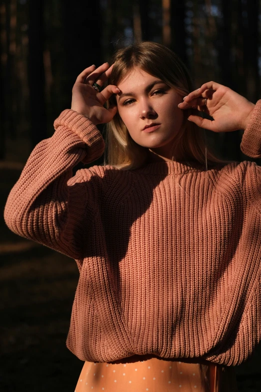 a woman in an orange sweater poses for the camera