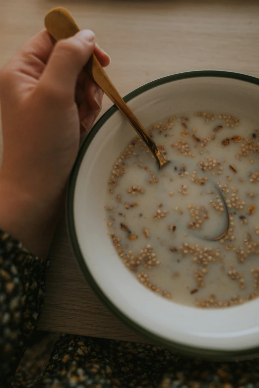 a person holding spoon in a bowl filled with cereal