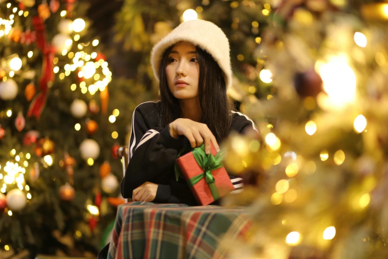 a woman sitting at a table in front of a christmas tree