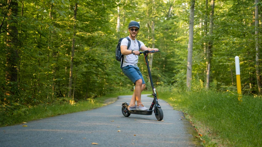 a man in a helmet is riding on a motorized scooter down the road