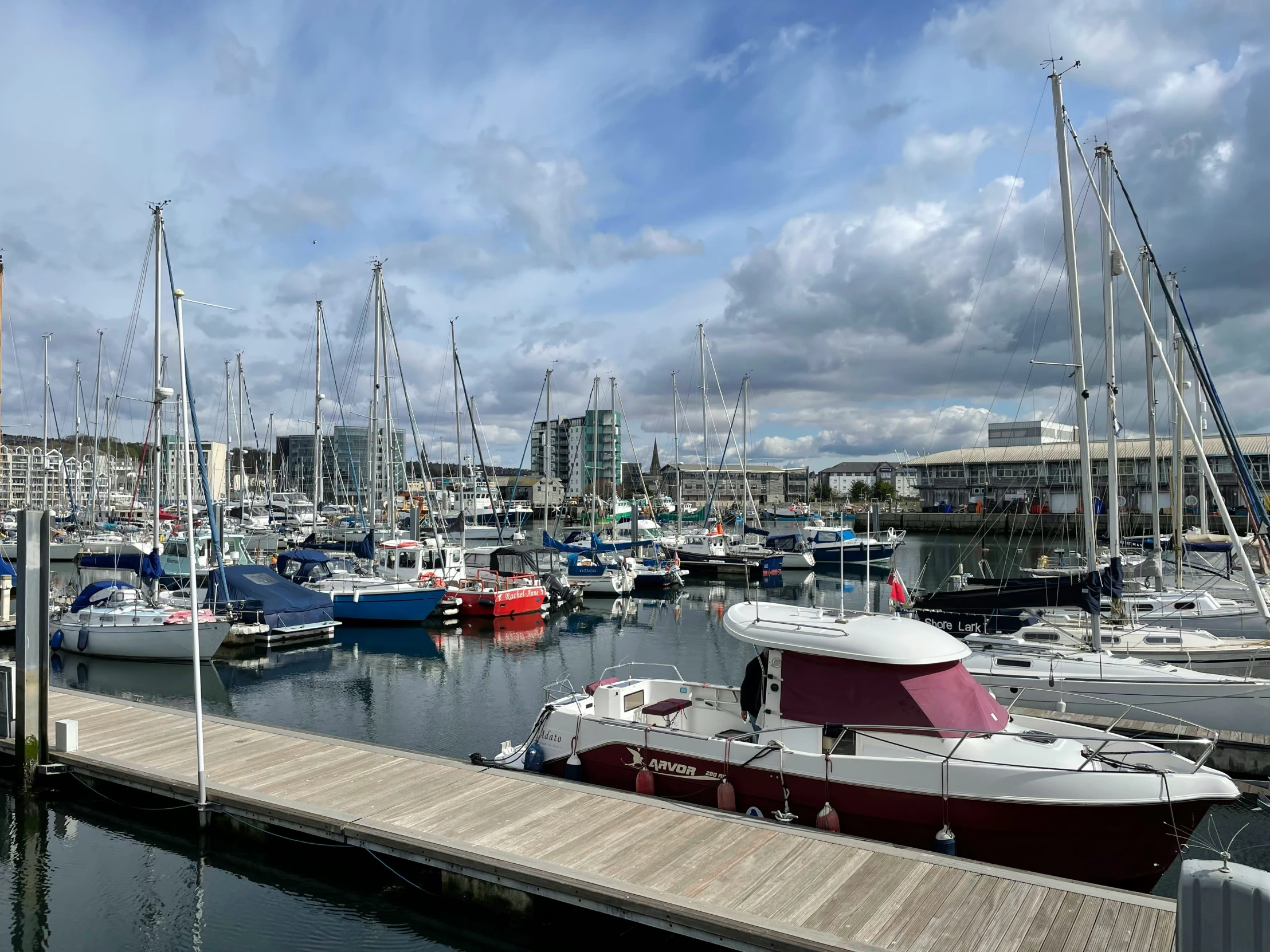 sailboats are docked in the harbor with buildings in the background