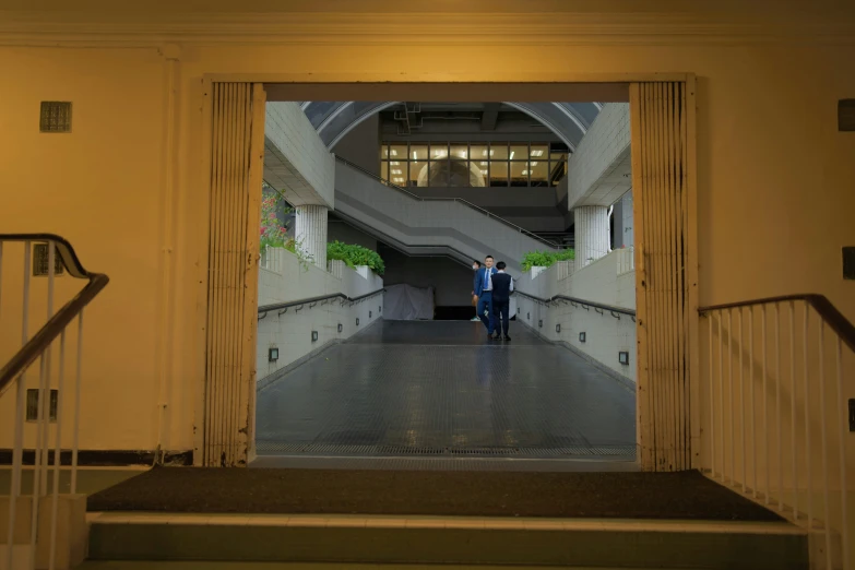 two people walking through an arched doorway on a staircase