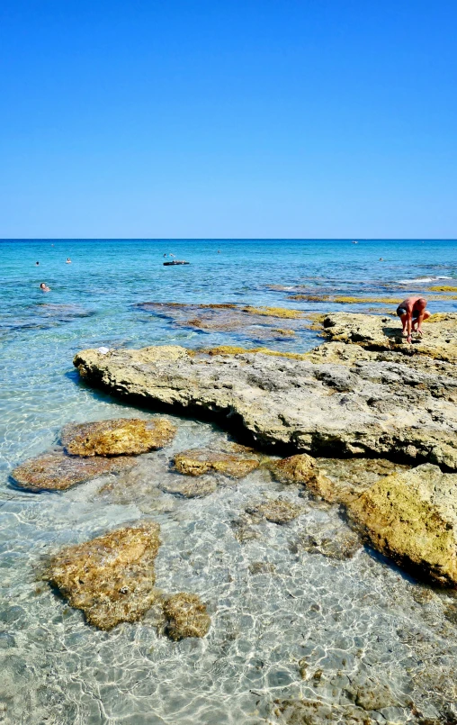 people playing in the clear water on the shore