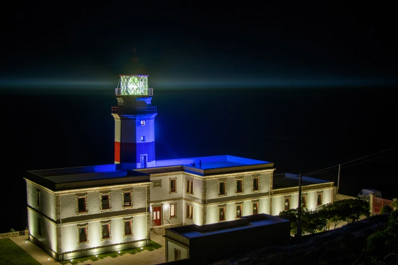 a lighted white building with a tower with a clock