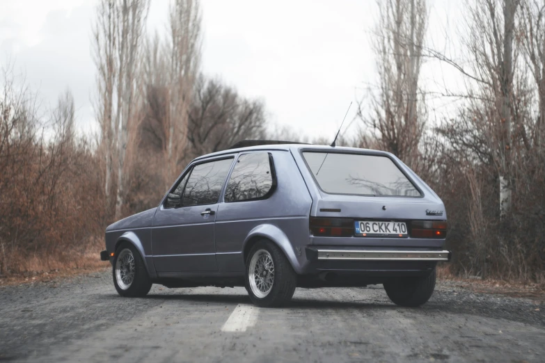 a small car sitting on the side of a road near trees