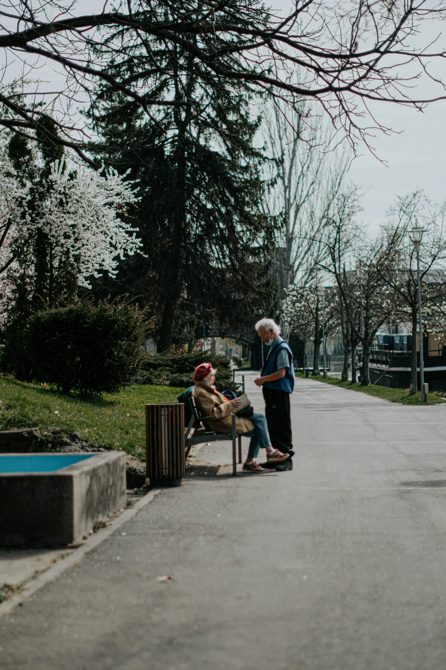 two elderly men sitting on a bench and one talking to each other