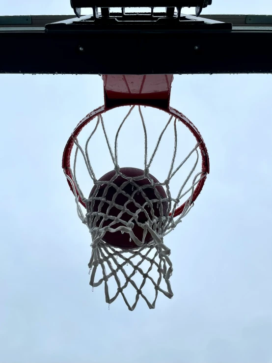 a basketball is in the hoop of an outdoor basketball goal