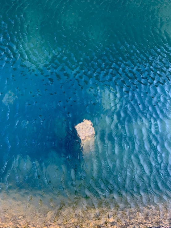 a blue ocean with clouds and water ripples over the water