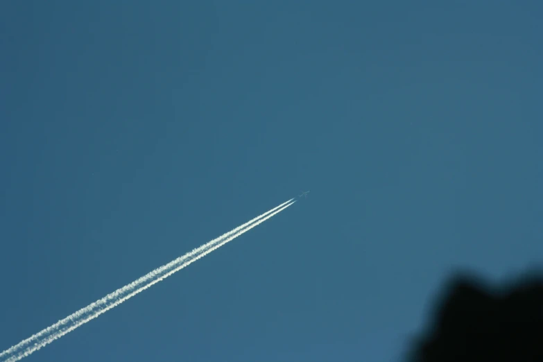 a jet flying in a clear sky with an contrail